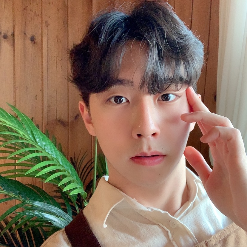 꽃이 놓인 책상 앞에서 웃고 있는 김남윤